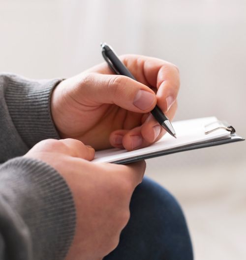 Una persona está escribiendo en un trozo de papel con un bolígrafo.