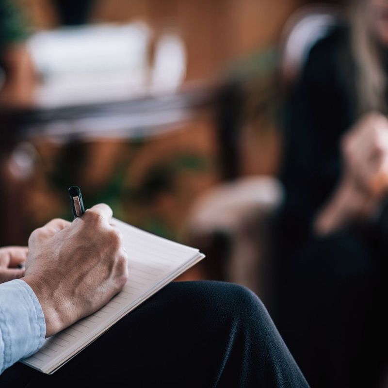 Una persona está escribiendo en un cuaderno con un bolígrafo.