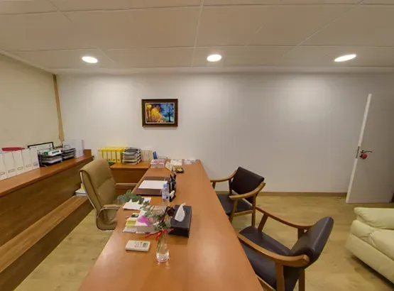 Una habitación con una mesa larga y sillas y un cuadro en la pared.