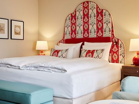 Unsere Junior Suite mit Ikat-Motiven Junior Suite im Strandhotel Zingst, mit großem Bett und geschwungenem Headboard mit Ikat-Motive.