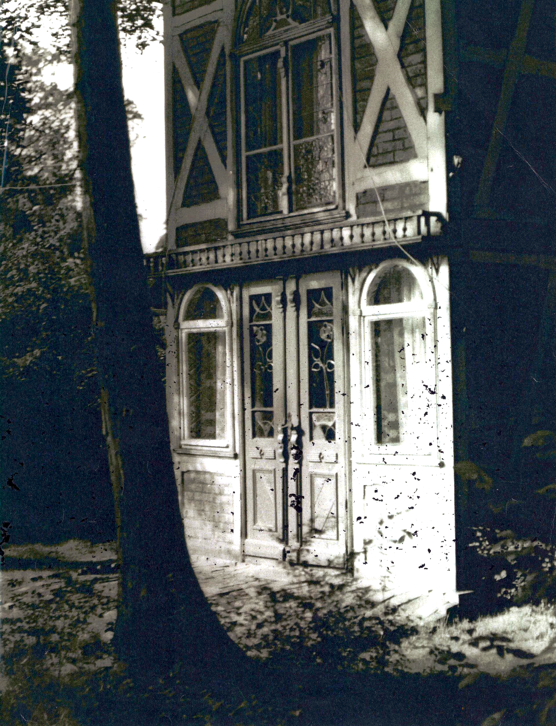 Person auf dem Balkon hält ein Weinglas und blickt auf das Zentrum von Zingst.