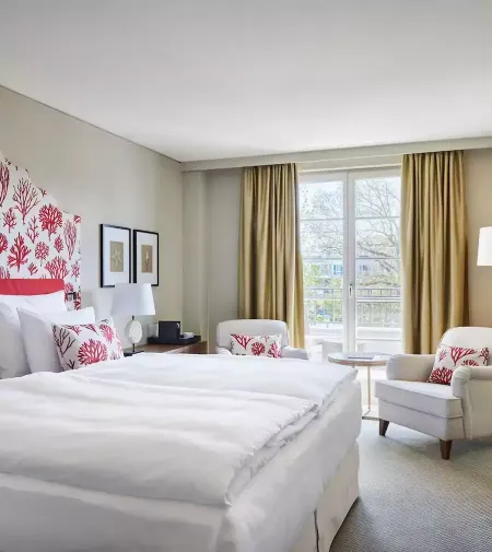 Gemütlich, hell und stilvoll - unsere Doppelzimmer Hotelzimmer mit einem großen Bett, zwei Sesseln und einen Ausblick in den Hotelgarten.