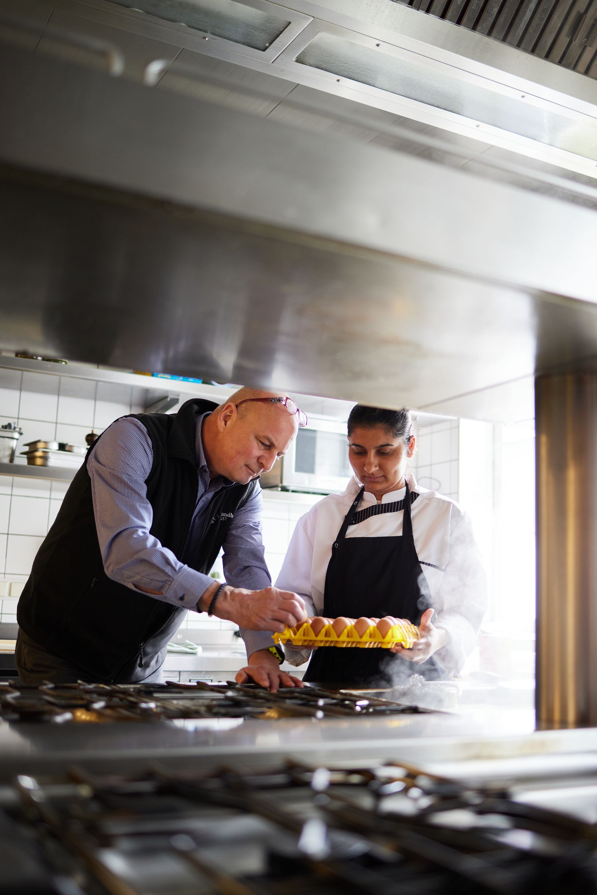 Hoteldirektor Kai Harmsen und eine Auszubildene stehen in der Küche und begutachten eine Palette mit Eiern.