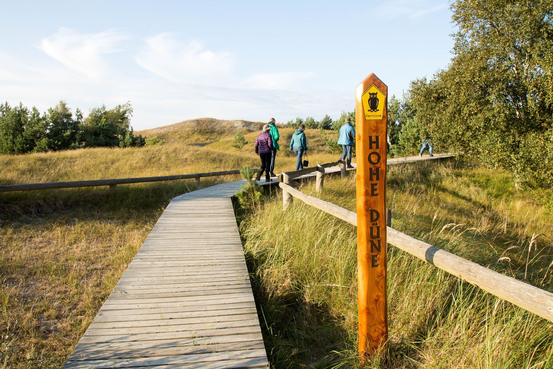 Wooden boardwalk path with hikers and sign for 