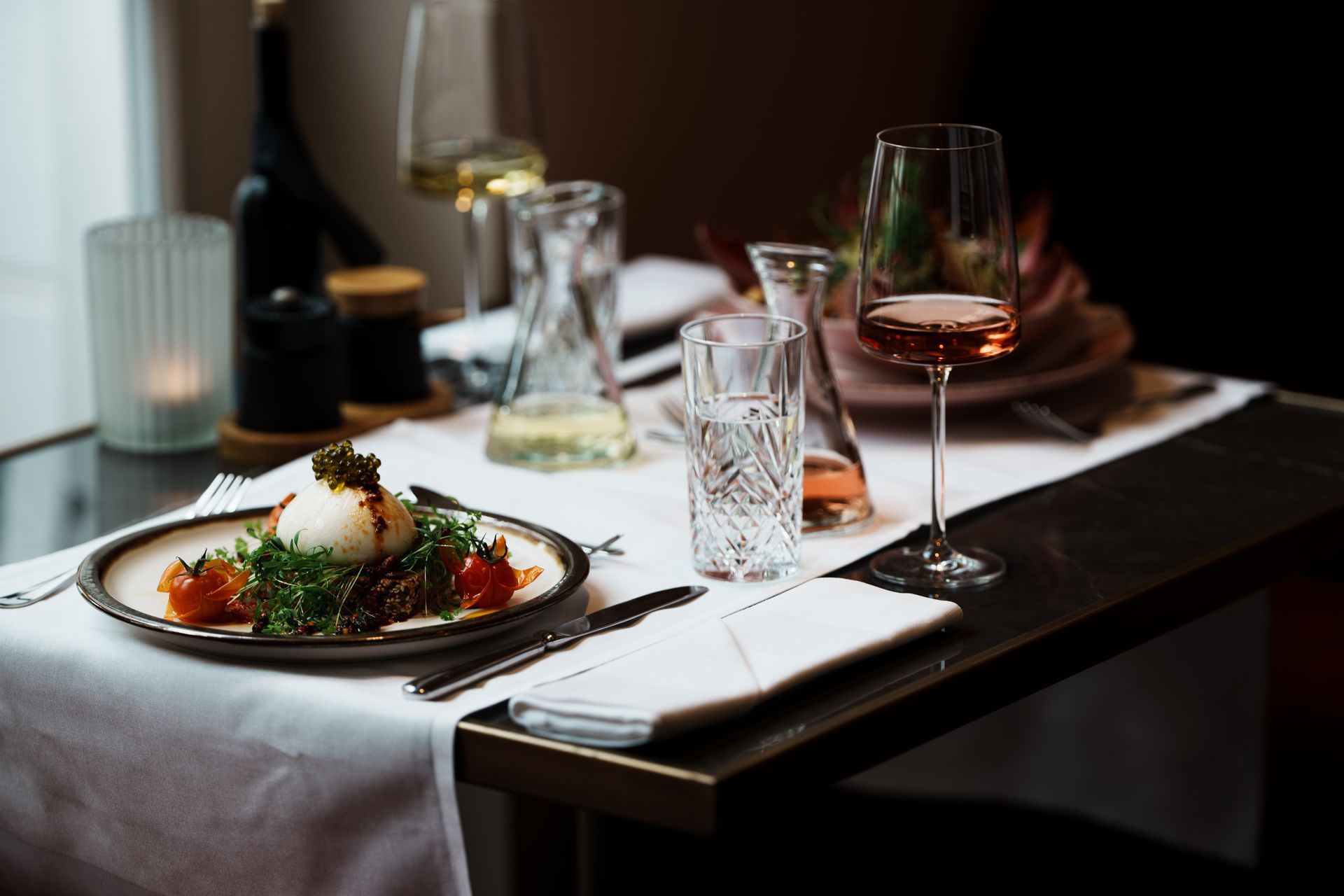 Der Tisch ist zum Abendessen gedeckt: ein Teller mit Essen, Gläser mit Wein und eine Kerze.