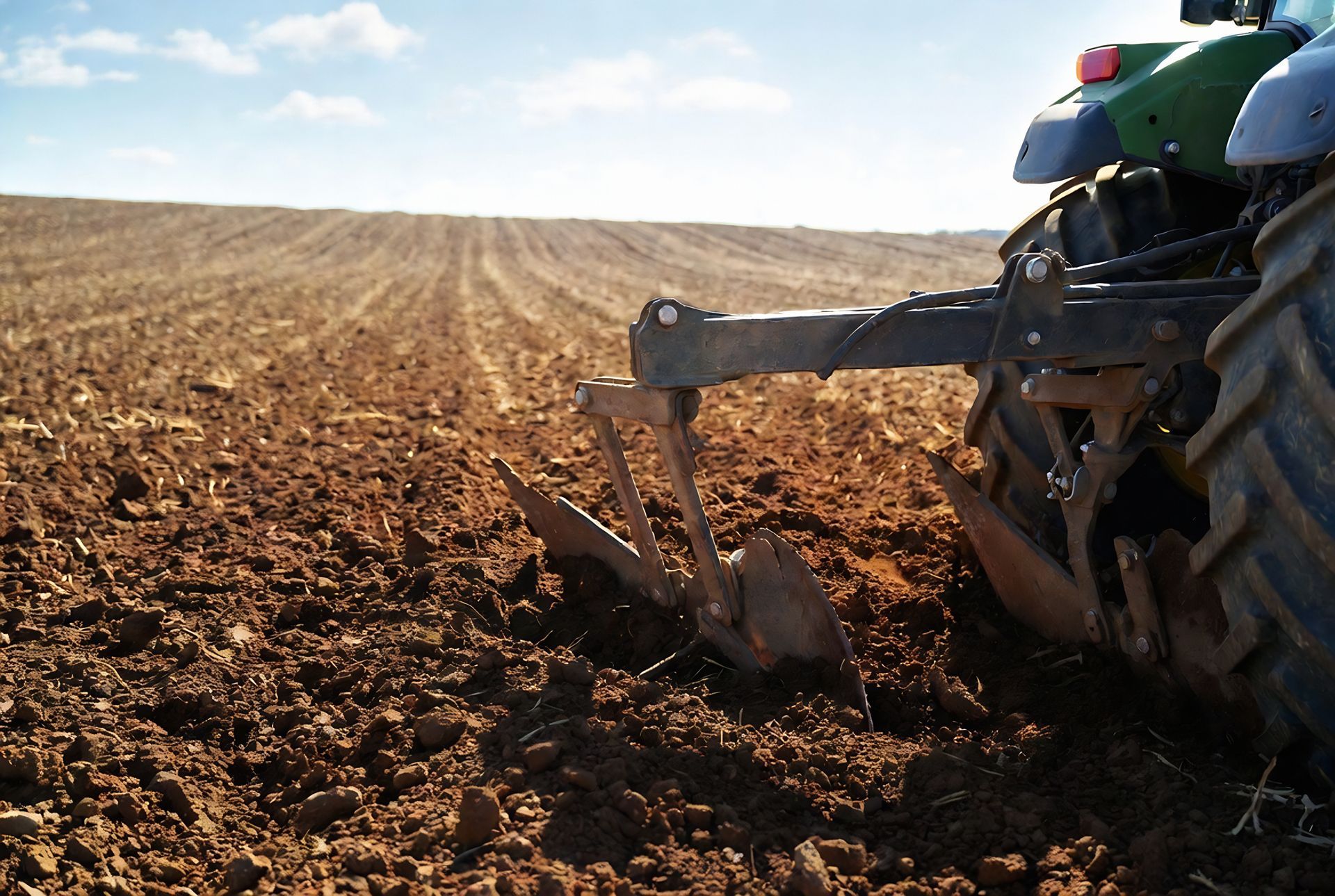 Tracteur labourant un champ sec sous un ciel dégagé.