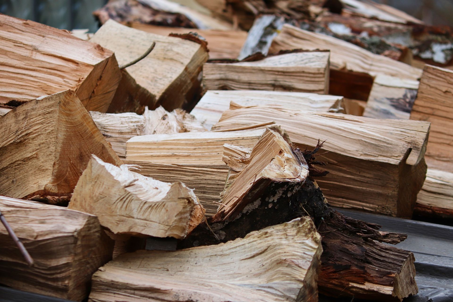 Gros plan de bûches de bois de chauffage coupées et empilées, aux extrémités rugueuses et fendues.