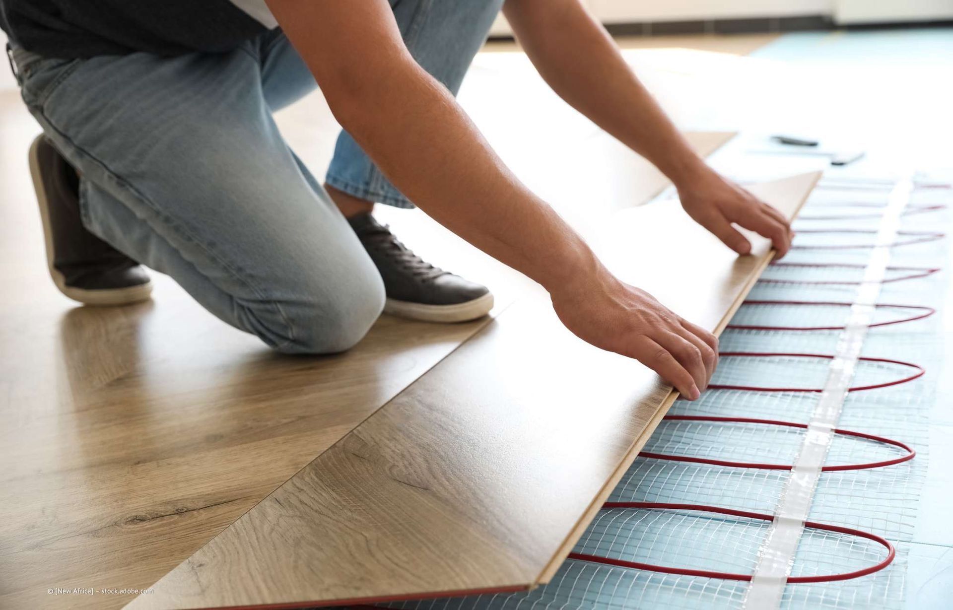 Person, die Holzfußböden über Heizkörpern verlegt.