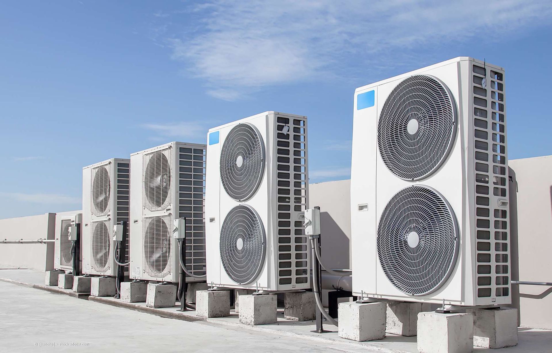 Klimaanlagen reihten sich auf einem Dach vor einem strahlend blauen Himmel auf.