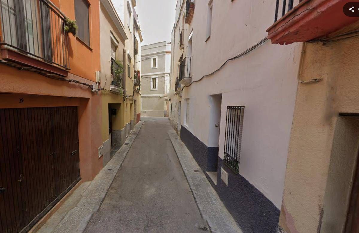 Callejón estrecho en una ciudad europea, bordeado de edificios de colores y texturas variados; la calle está vacía.
