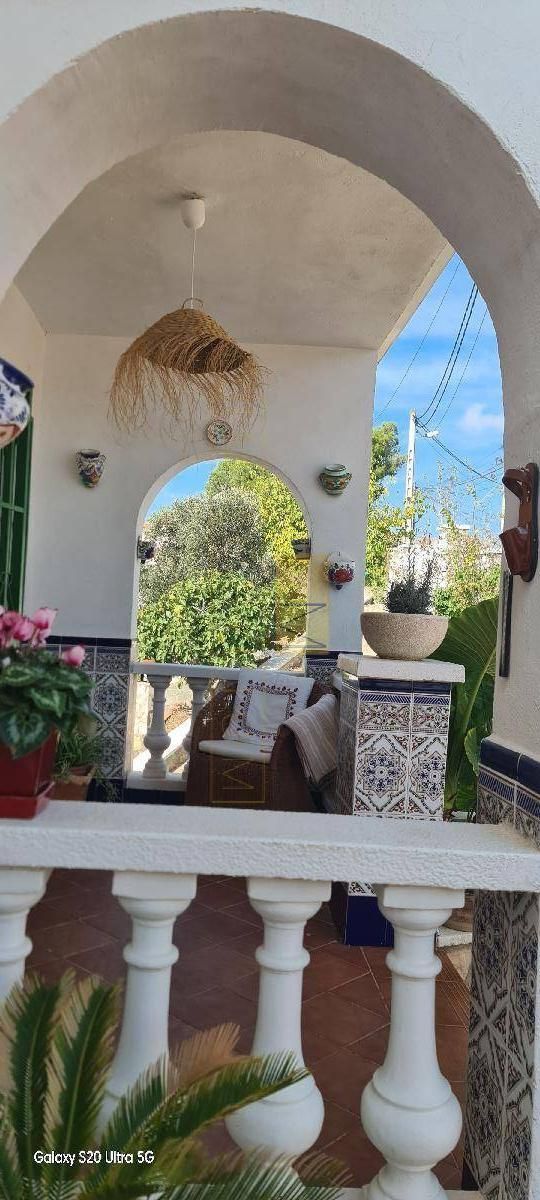 Porche con arco, plantas, decoración colgante y vista al cielo.