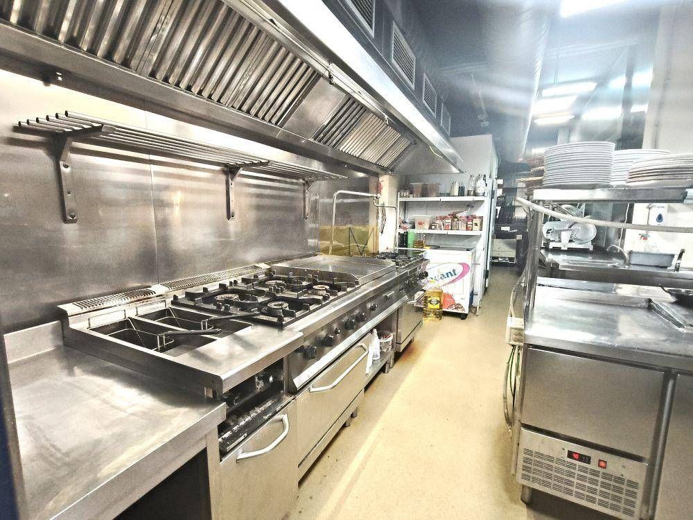 Cocina comercial con electrodomésticos de acero inoxidable y campana extractora.