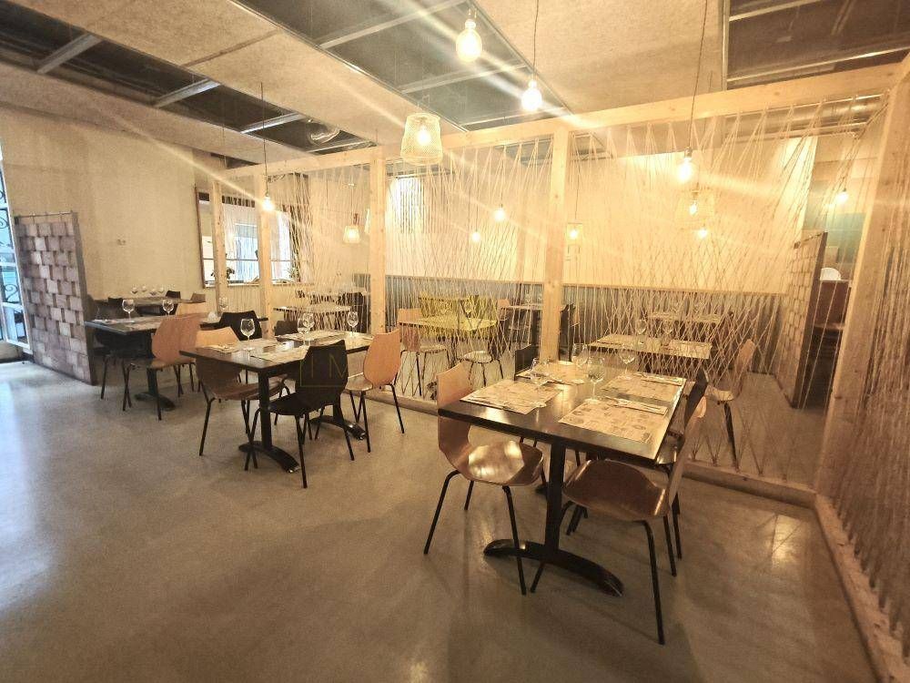 Interior de restaurante con mesas, sillas y separadores de cuerda. Iluminación natural brillante.