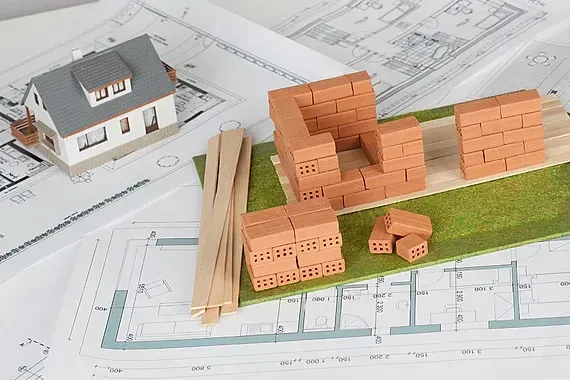Hay un modelo de una casa y un modelo de una pared de ladrillos.