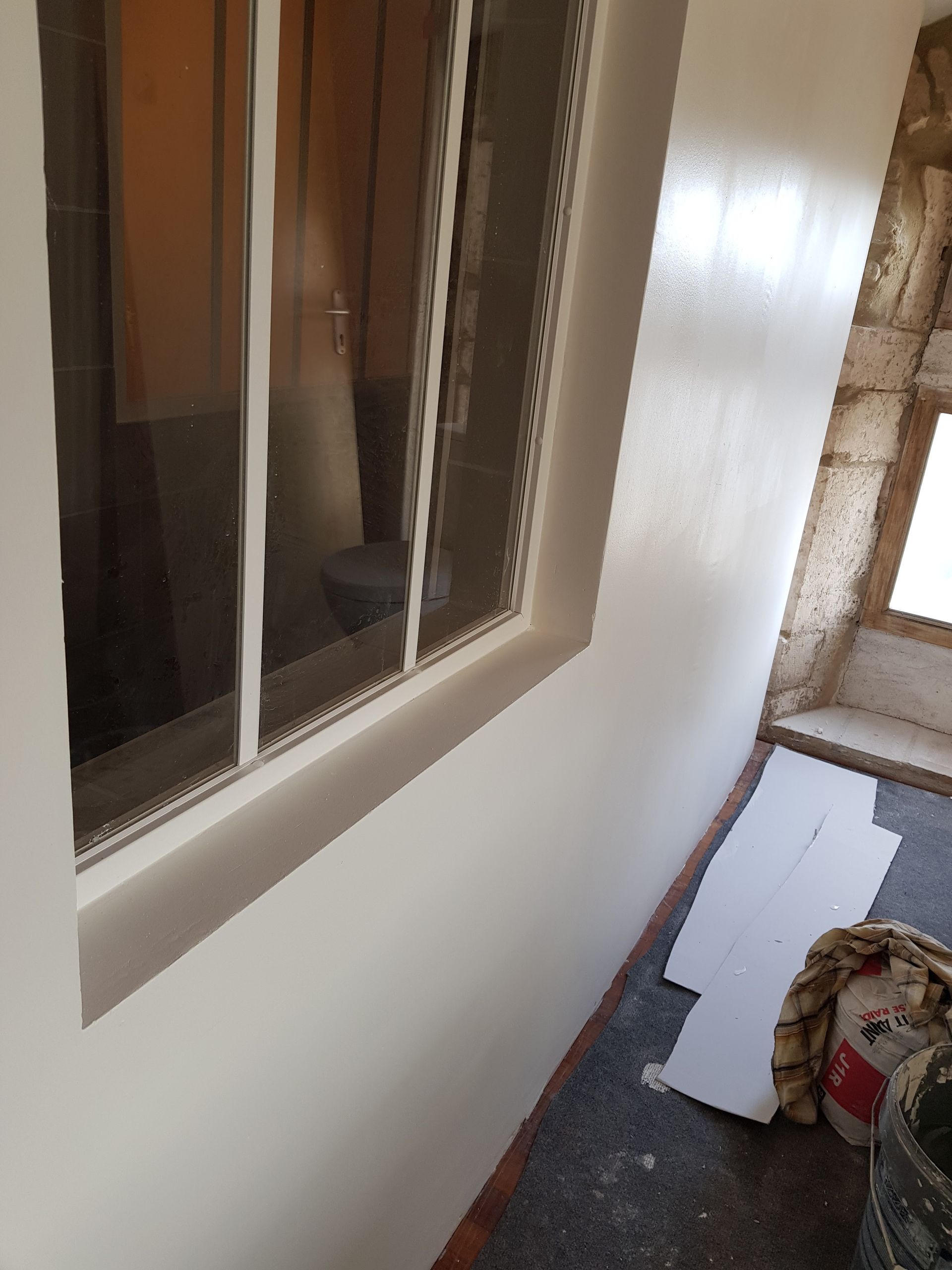 Mur intérieur peint en blanc avec une fenêtre, comptoir sombre avec des matériaux de qualité.