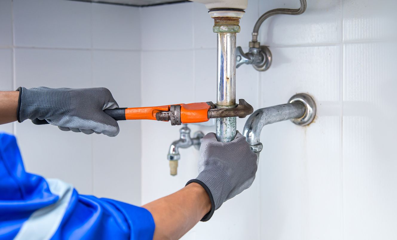 Tuyaux et outils à l'intérieur d'un mur. Tuyaux bleus, rouges et argentés avec une boîte à outils au sol.