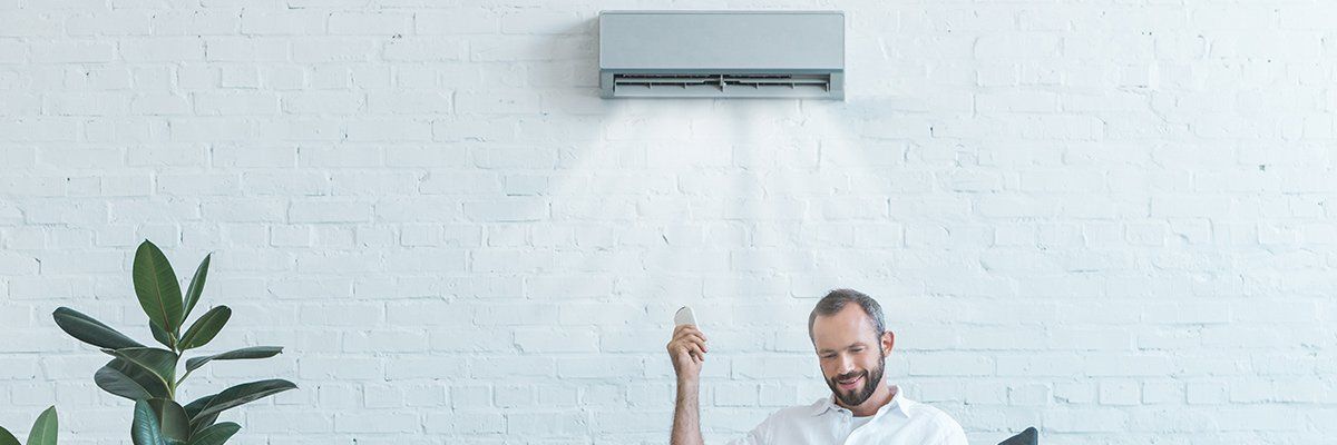 Un homme qui actionne une climatisation avec sa télécommande