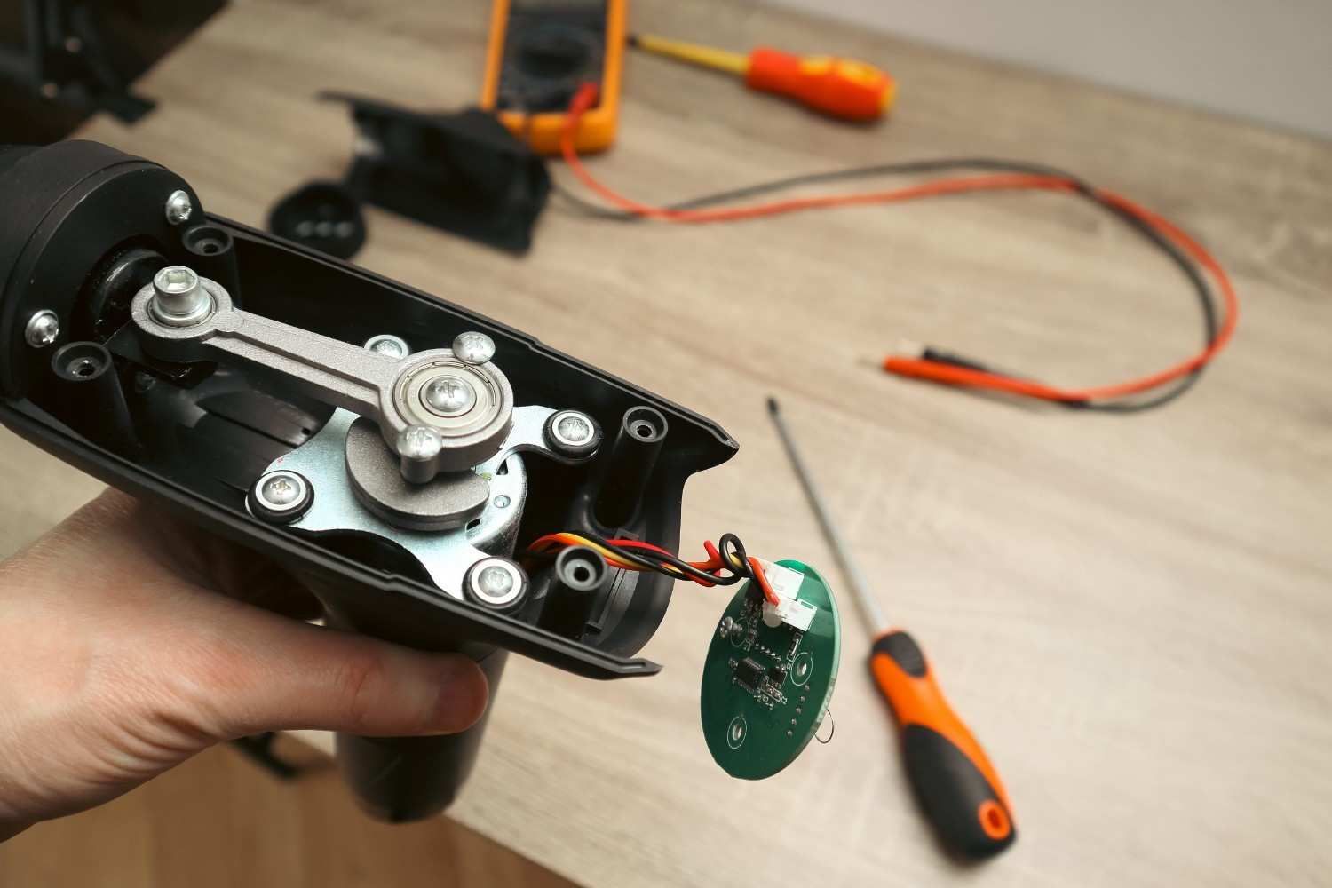 Una persona sostiene una herramienta eléctrica abierta, dejando al descubierto los engranajes mecánicos internos.