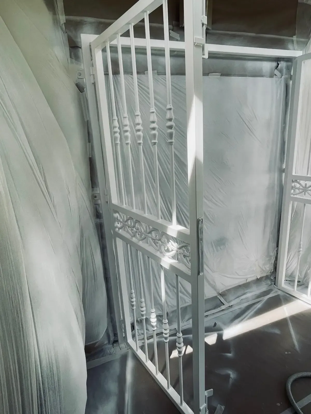 Puerta de seguridad de metal blanco junto a una puerta en un luminoso pasillo interior.