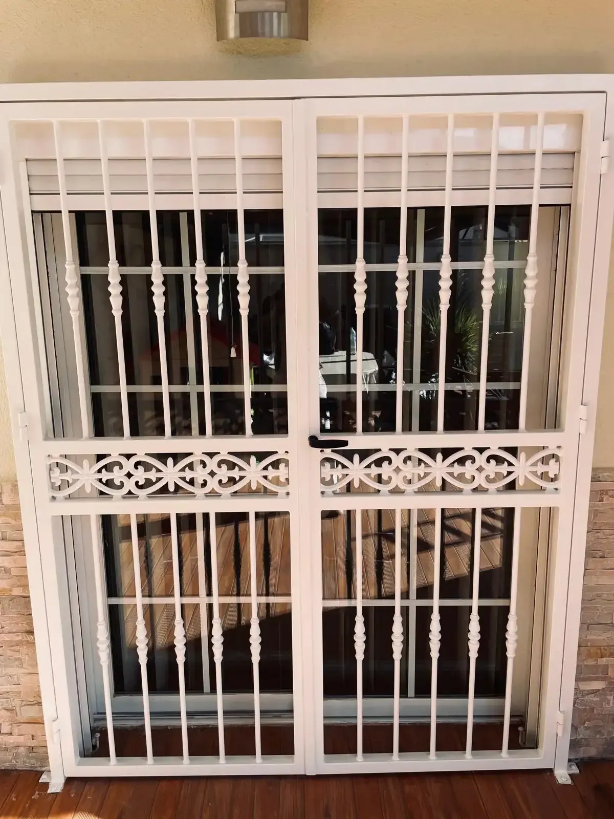 Reja de seguridad decorativa blanca en una ventana, con barrotes verticales y un diseño de celosía floral.