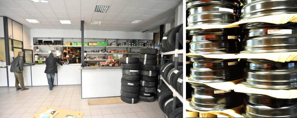 Intérieur d'un magasin de pneus. Clients au comptoir, pneus empilés et jantes sur des étagères.