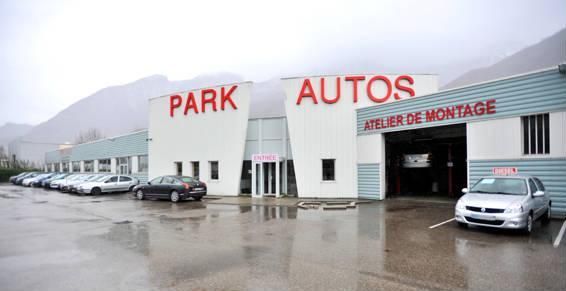 Concessionnaire automobile Park Autos avec des voitures garées à l'extérieur ; enseigne « Atelier de Montage ».