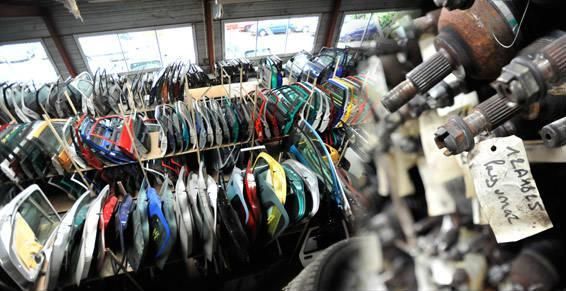 Des rangées de pièces automobiles, étiquetées, suspendues dans ce qui semble être une casse ou un magasin de pièces automobiles.