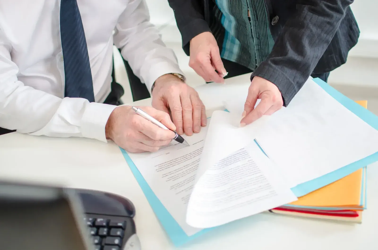 Un hombre y una mujer están sentados en una mesa firmando un documento.