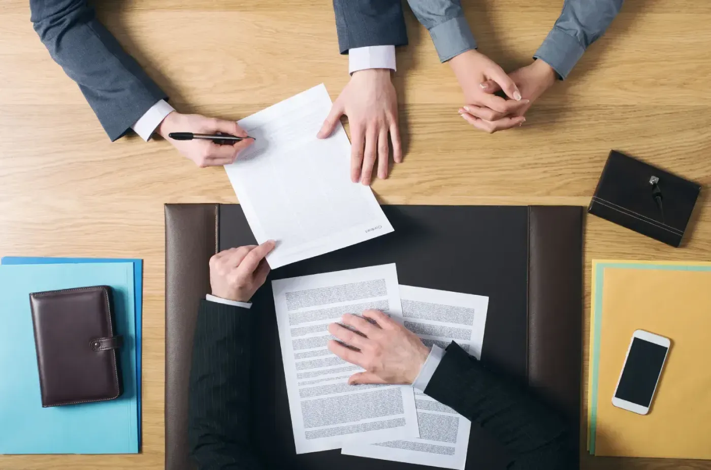 Un grupo de personas está sentada en una mesa firmando un documento.