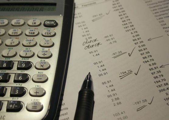 Una calculadora se encuentra encima de una hoja de papel que dice comprobar