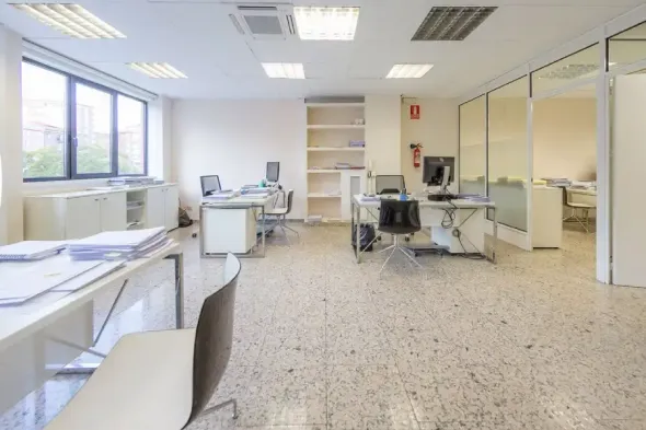 Una oficina grande con muchos escritorios y sillas.