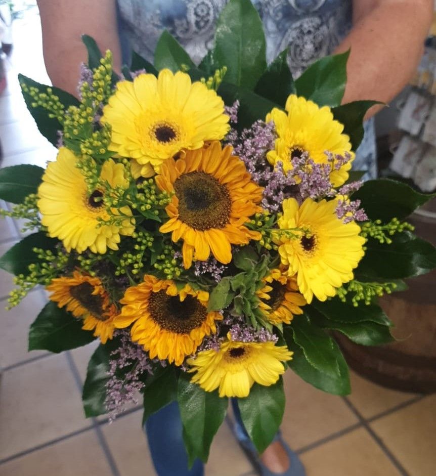 Eine Person bindet einen Blumenstrauß auf einem Tisch.
