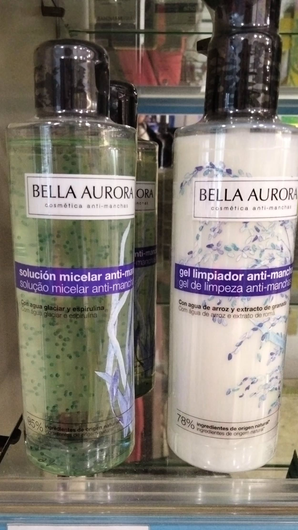 Dos frascos de gel micelar limpiador de Bella Aurora en un estante de una tienda, uno verde y otro blanco, con etiquetas de precio debajo.