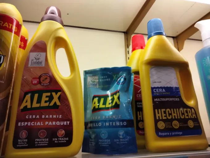 Varias botellas de aerosol de productos de limpieza de colores variados, agrupadas sobre un fondo blanco.