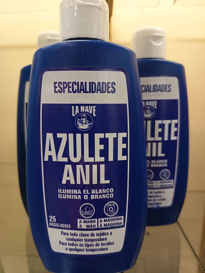 Varias botellas de aerosol de productos de limpieza de colores variados, agrupadas sobre un fondo blanco.