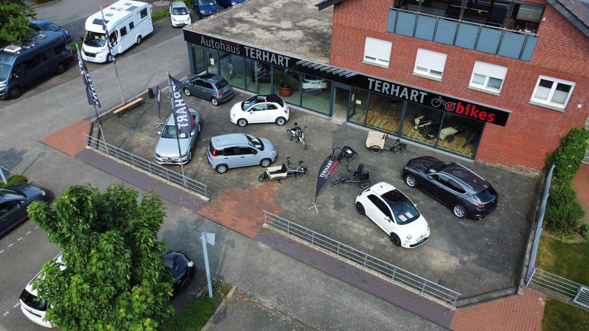 Eine Luftaufnahme eines Autohauses mit davor geparkten Autos.
