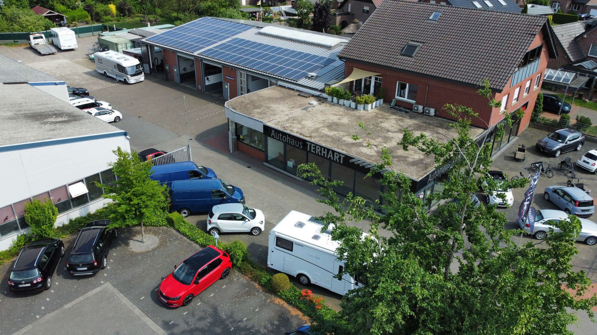Eine Luftaufnahme eines Parkplatzes mit vor einem Gebäude geparkten Autos.
