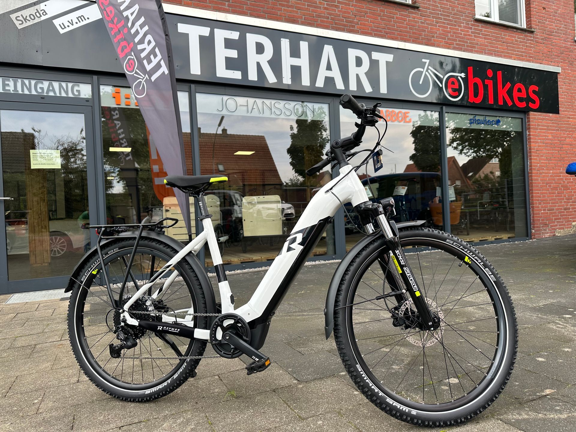 Ein weißes Elektrofahrrad steht vor einem Geschäft.