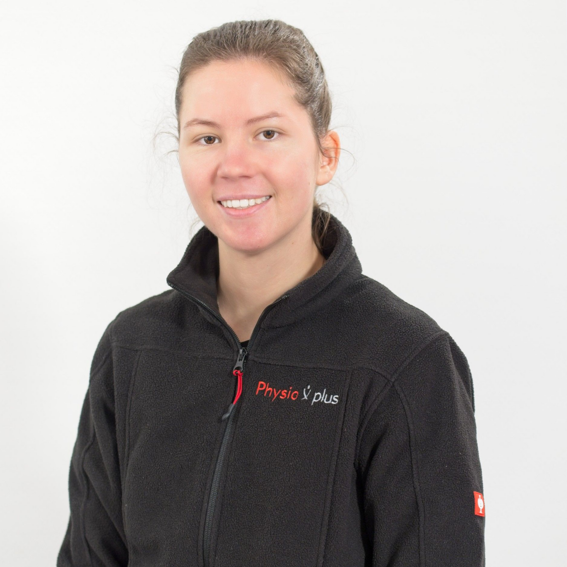 Eine Frau in einem roten T-Shirt lehnt an einer Wand.