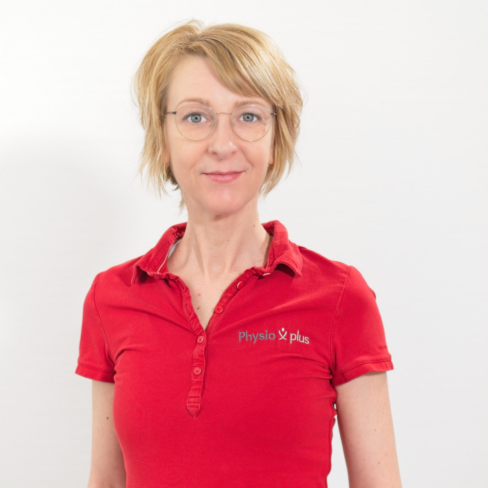 Eine Frau in einem roten Hemd lehnt an einer Wand.