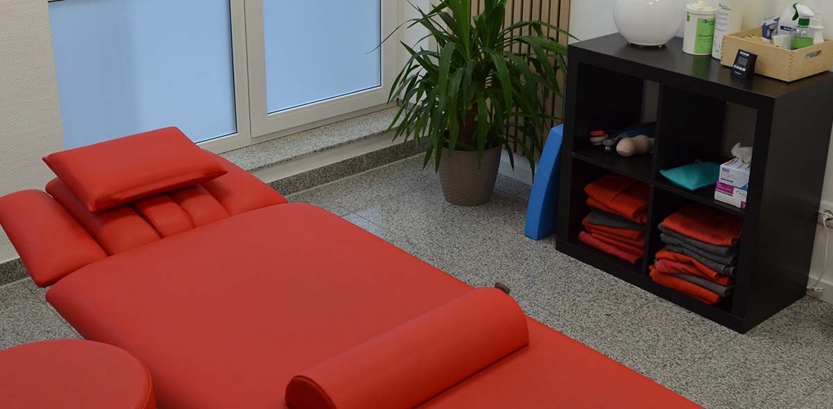 Ein Zimmer mit einem roten Bett und einer Pflanze