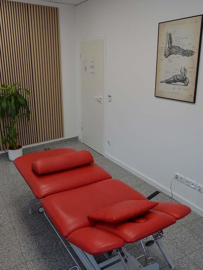 Eine rote Massageliege in einem Raum mit einem Bild an der Wand