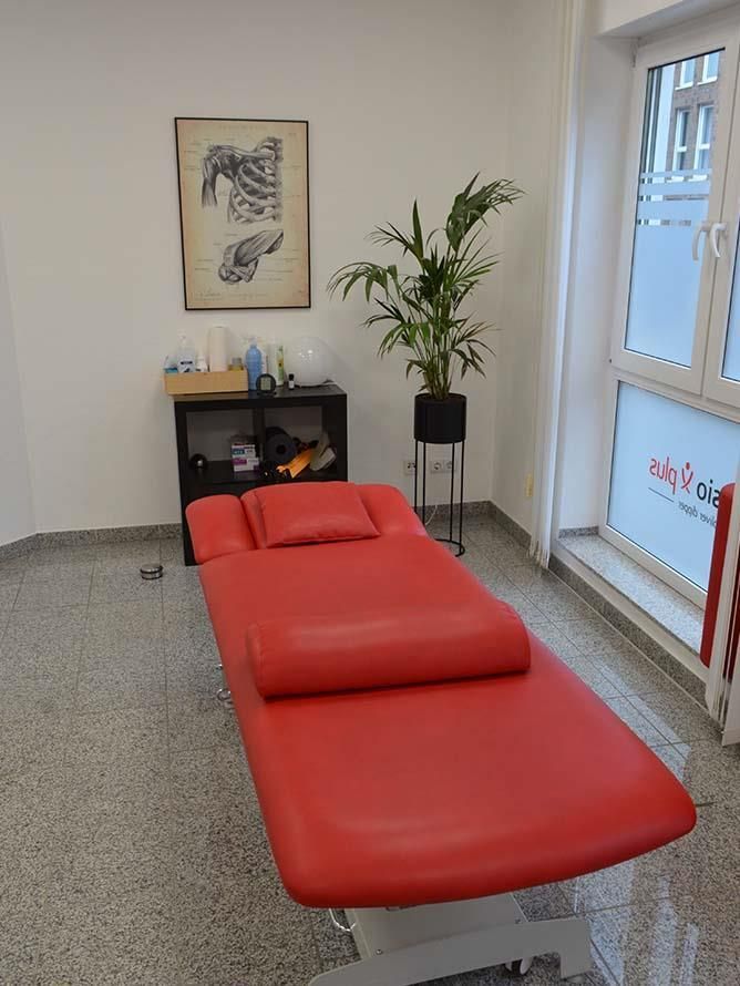 Eine rote Massageliege in einem Raum mit einer Pflanze