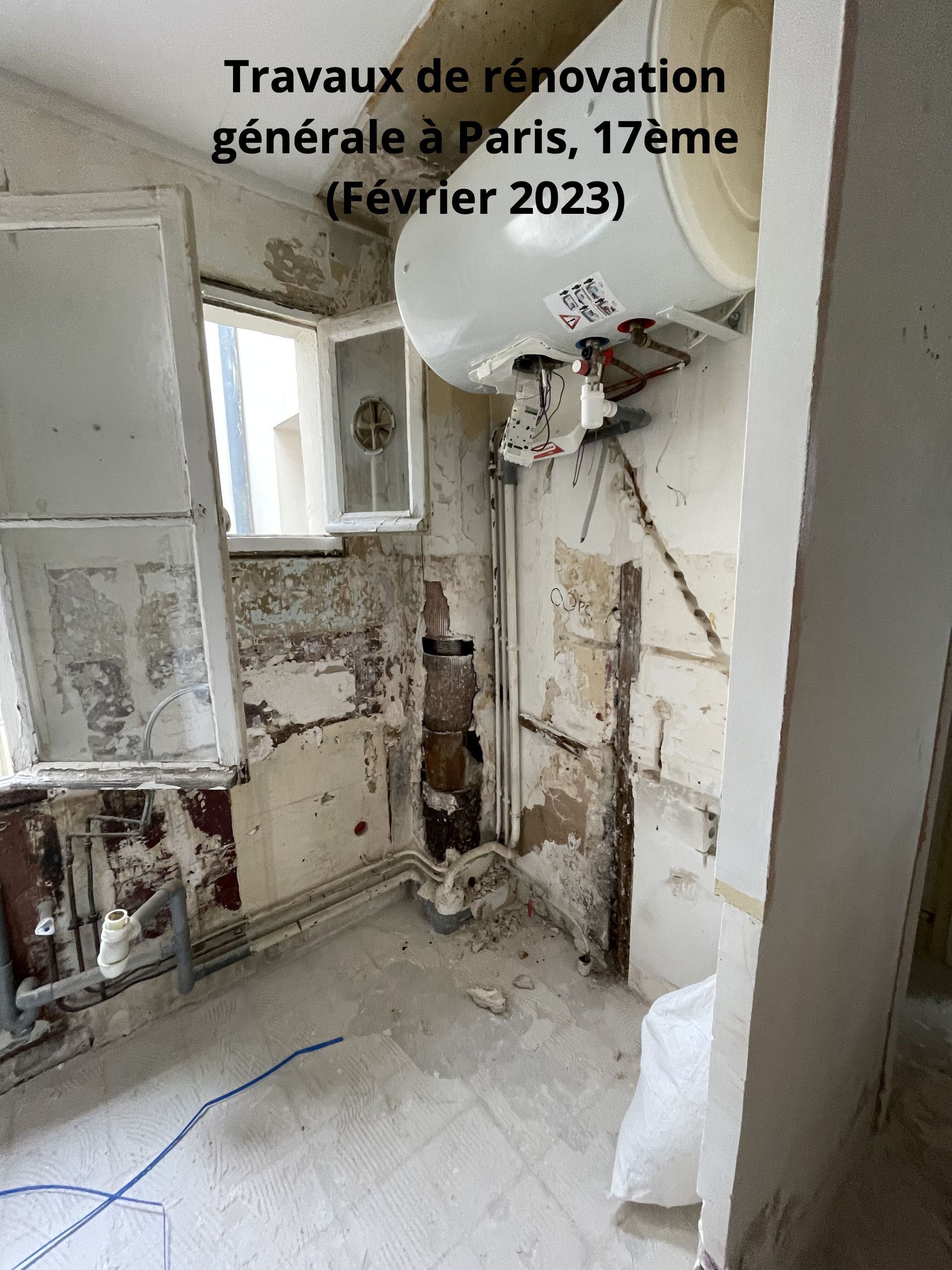 Travaux de rénovation dans une pièce à Paris, 17e arrondissement. Murs à la peinture écaillée, chauffe-eau et débris. (Février 2023)