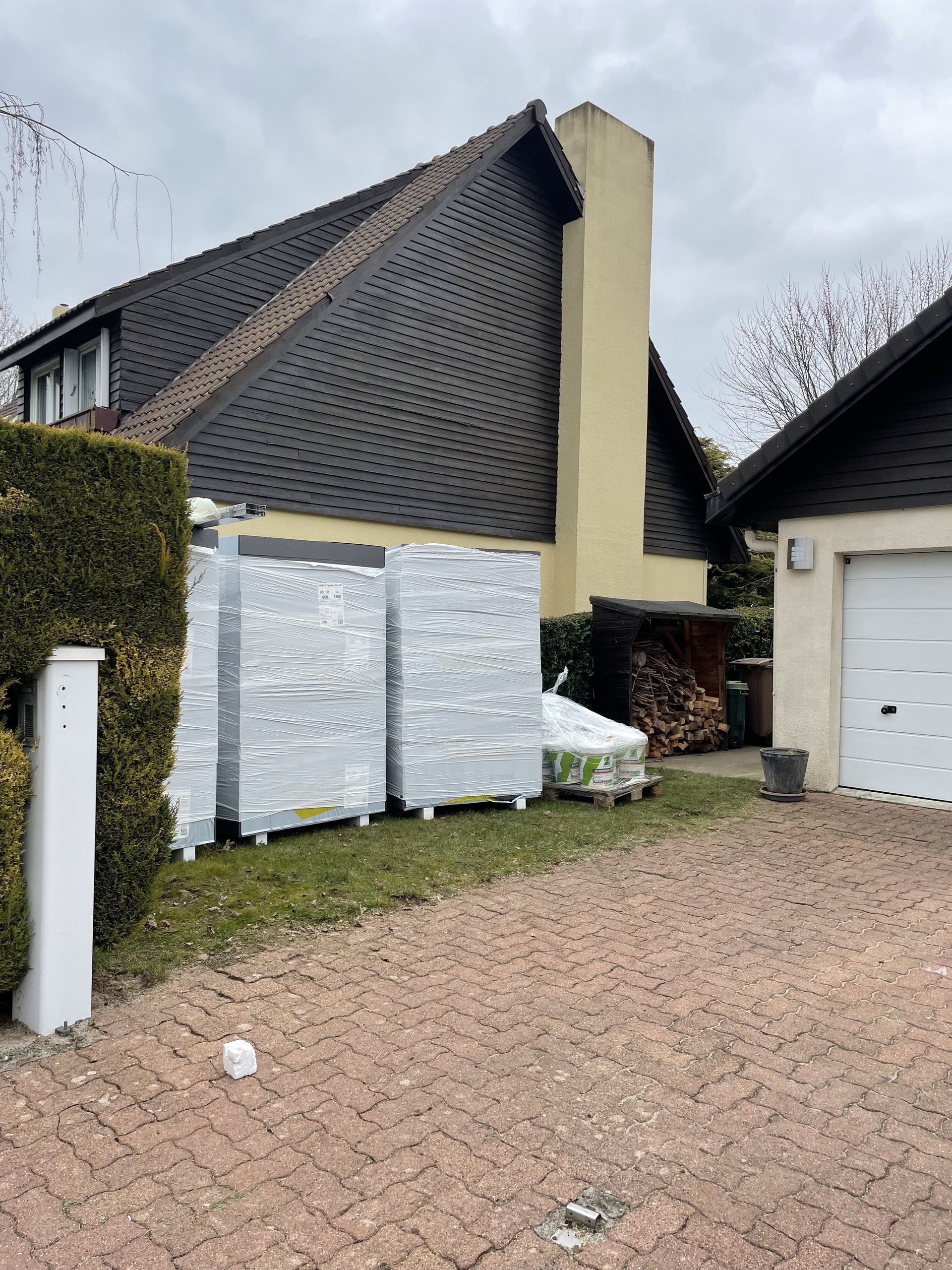 Des paquets emballés dans du papier aluminium sont posés sur une allée en briques devant une maison.