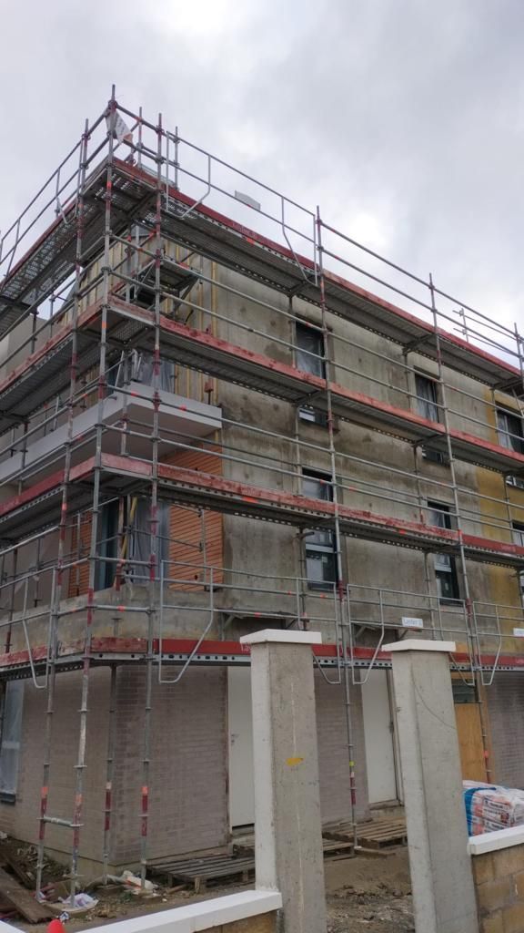 Bâtiment en rénovation avec échafaudages ; ciel nuageux.