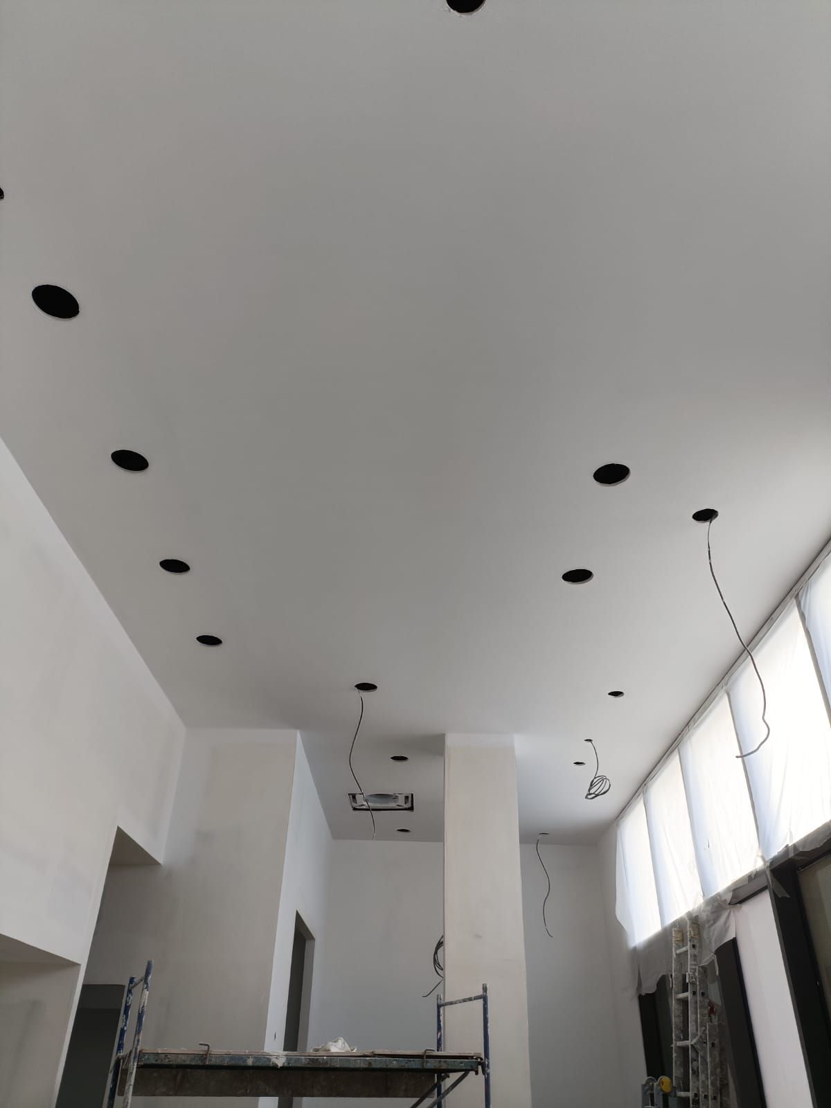 Plafond blanc avec spots encastrés noirs. Fils électriques apparents. Pièce en travaux.