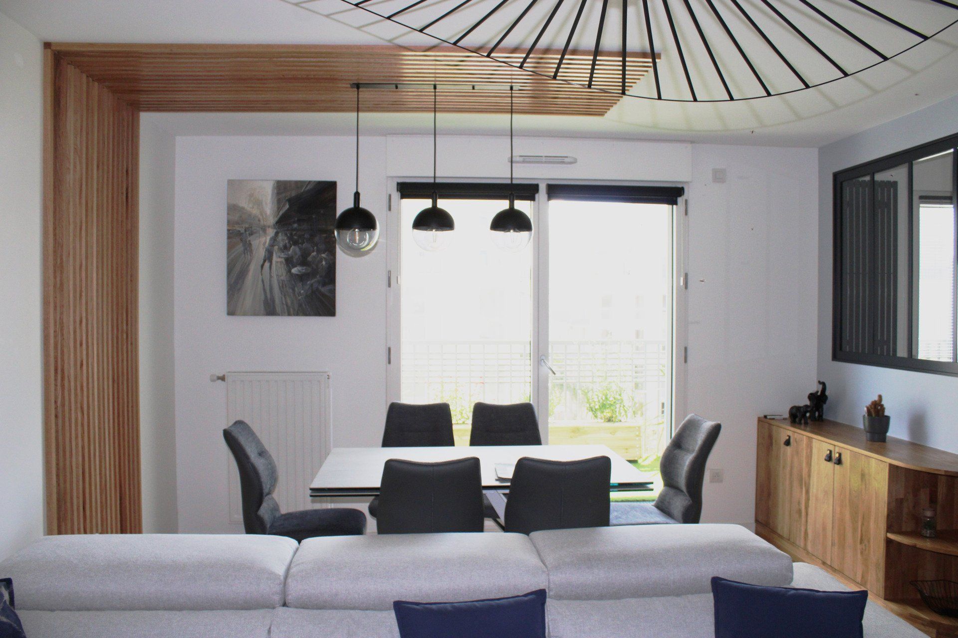 Salle à manger avec murs blancs, éléments en bois et une table dressée pour quatre personnes.