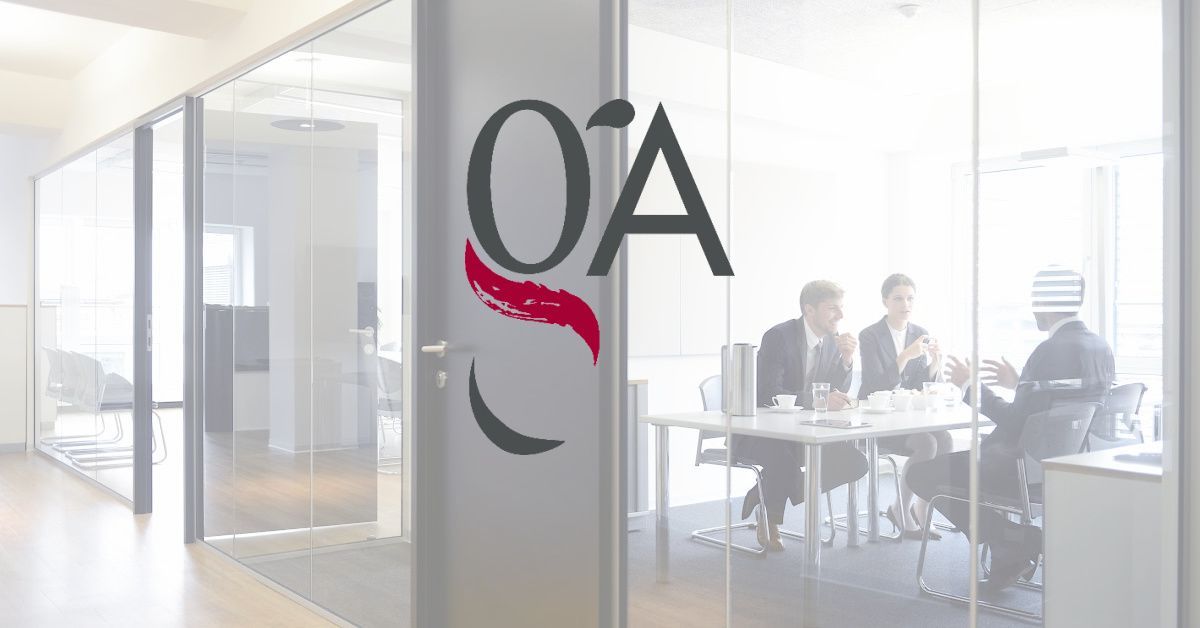 Oficina de cristal con el logo "OSA"; personas con traje en una mesa.