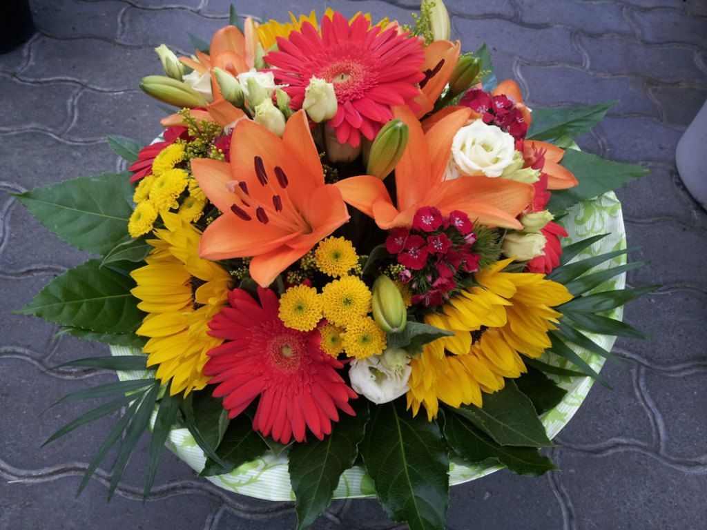 Farbenfrohes Blumenarrangement mit Sonnenblumen, Lilien und Gerbera.
